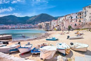 Sunny ligurian beach with houses and boats on sand. Italy