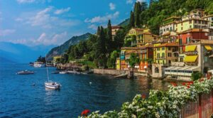 Sunny colorful houses on a cliff by the sea in Liguria, boats on the water.